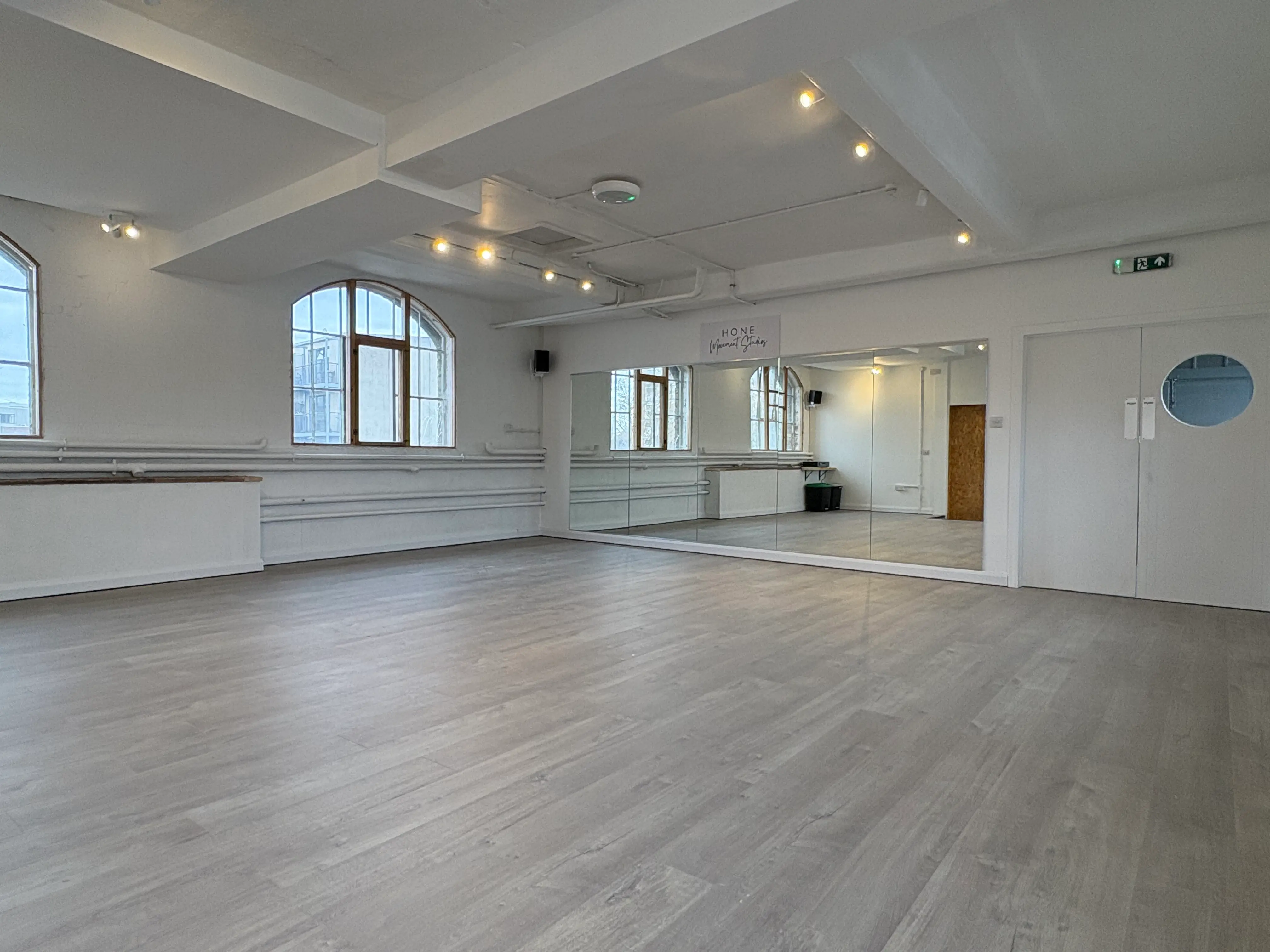 Studio 49 — empty studio looking back, full-height mirrors and arched warehouse windows